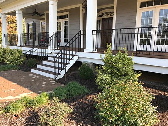 a white house with black railings and steps leading up to the front porch area