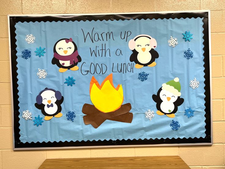 a bulletin board with penguins around a campfire and saying warm up with a good lunch