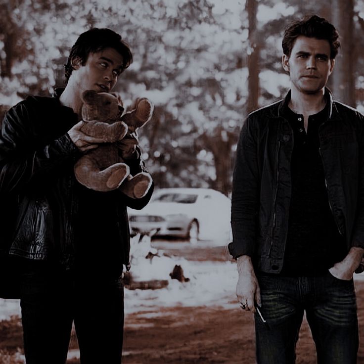 two men standing next to each other holding teddy bears