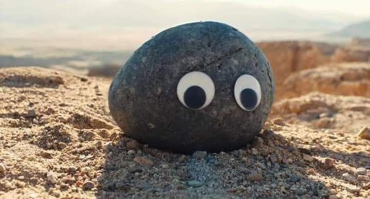 a rock with googly eyes sitting in the sand