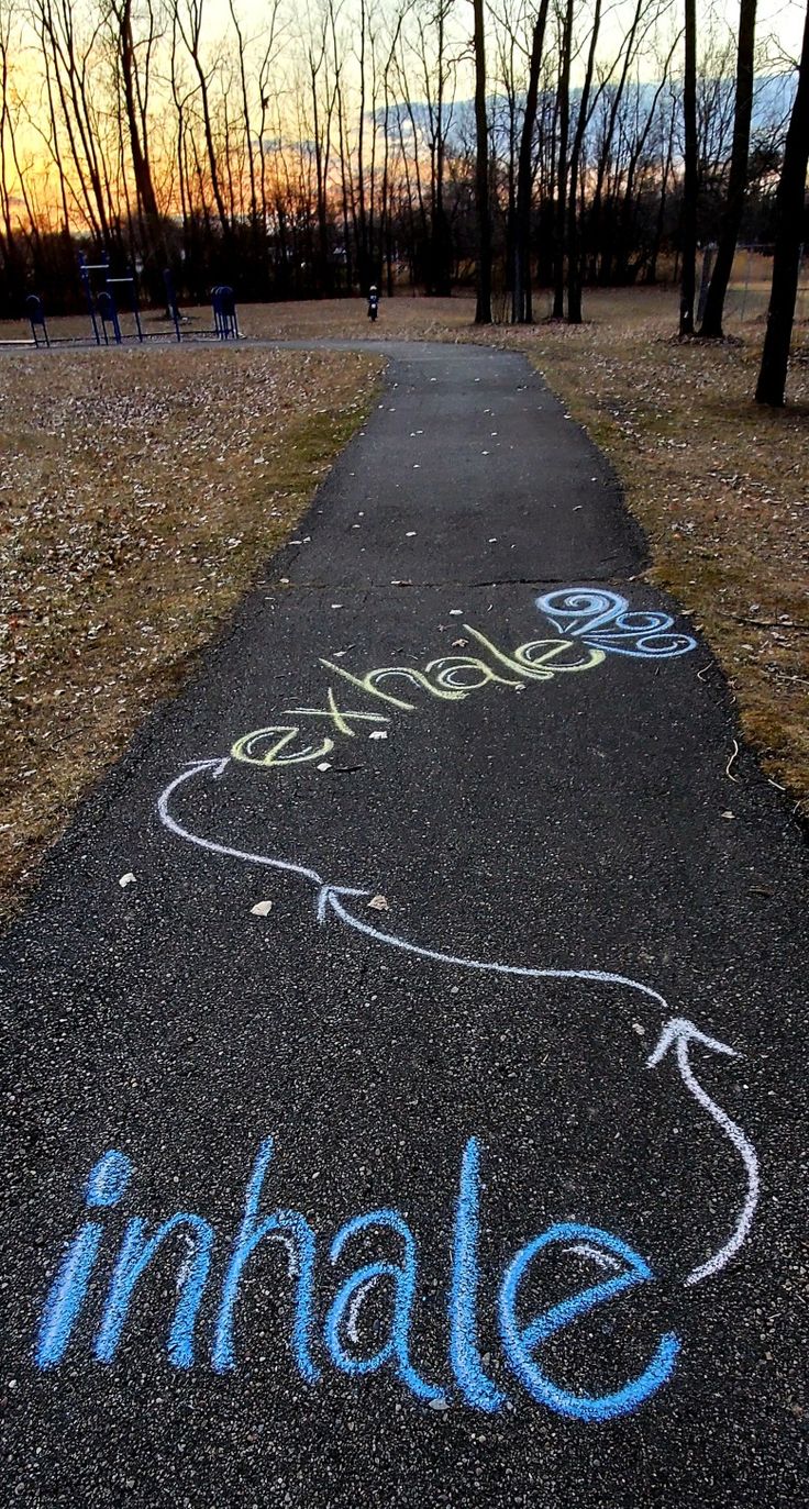 the sidewalk has chalk writing on it that says imhale and an arrow drawn on it