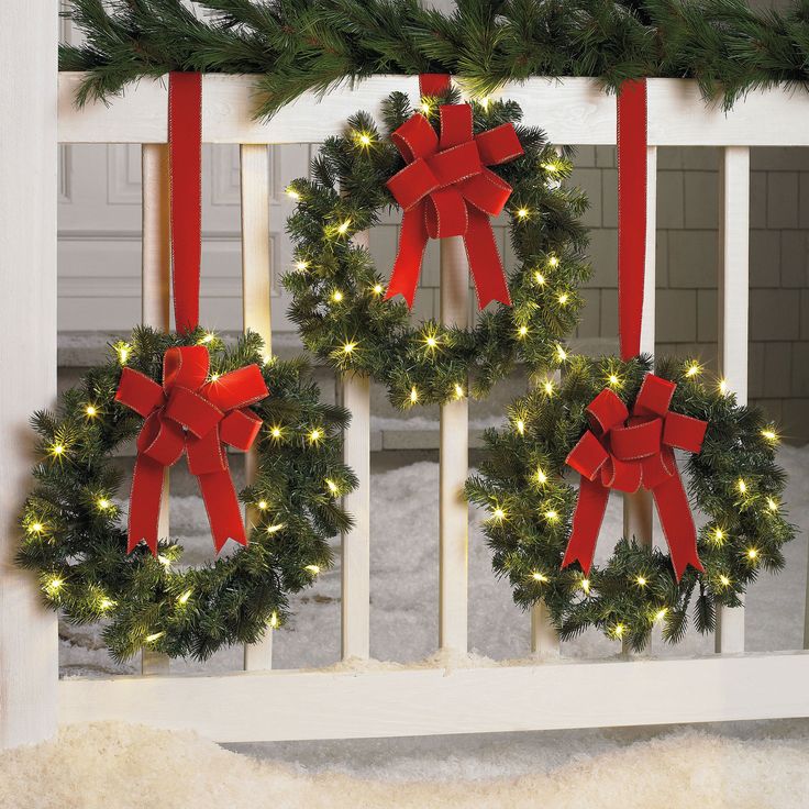 an ad for christmas wreaths on the front of a window with red bows and lights