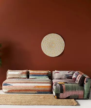 a living room with a couch and rug in front of a wall that has a circular painting on it