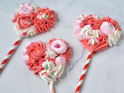 three candy lollipops are arranged on a marble counter top with candy canes in the shape of hearts