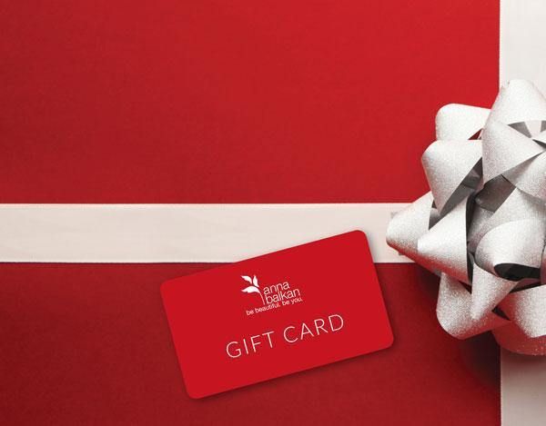 a red and white gift card with a bow on it next to a wrapped present