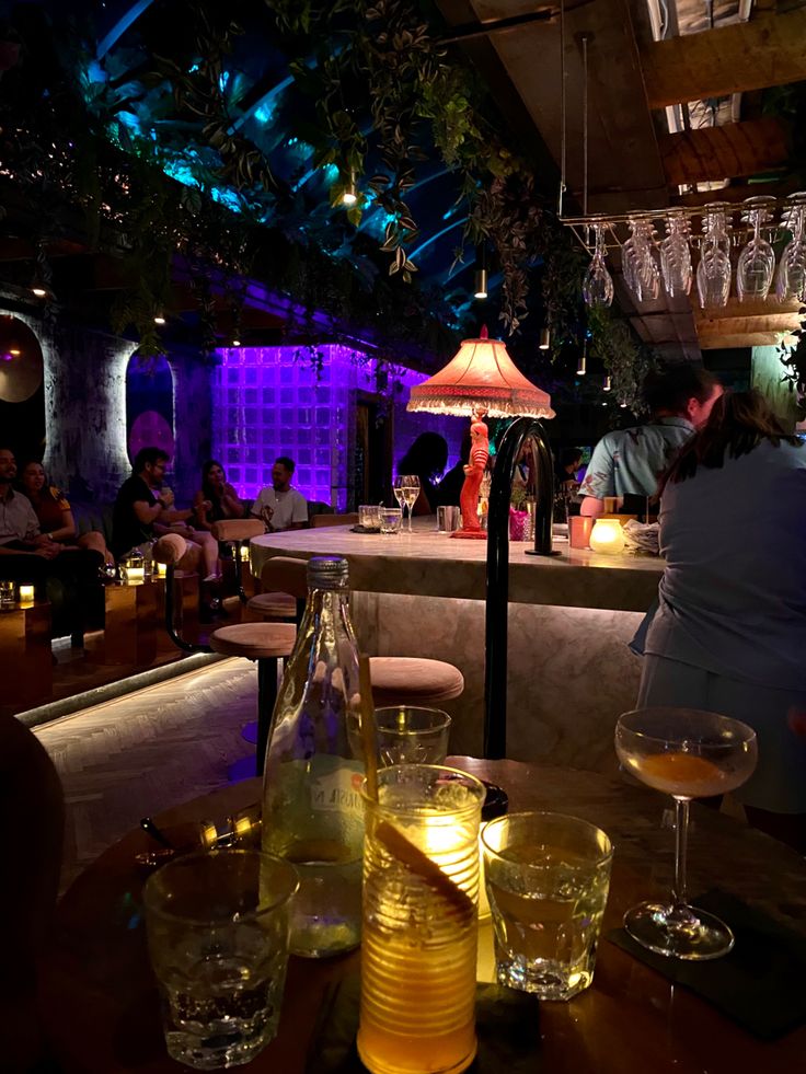 people are sitting at a bar with wine glasses on the table