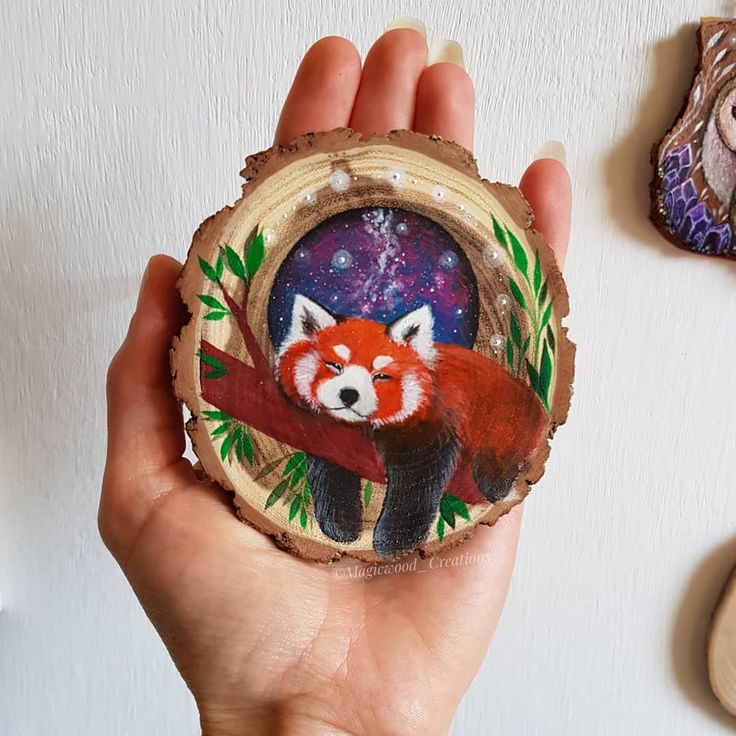 a hand holding a piece of wood with a red fox on it