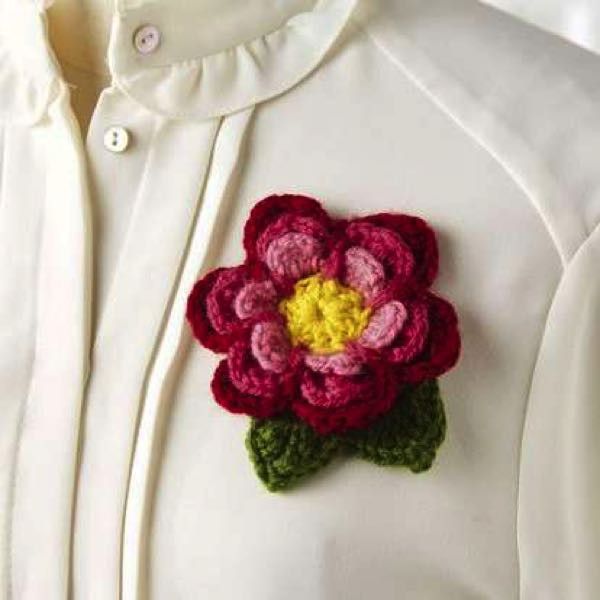 a crocheted flower is attached to the collar of a white shirt with buttons