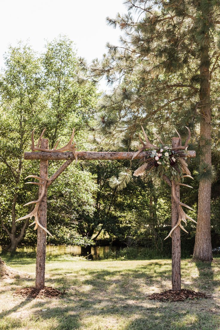 an outdoor ceremony setup with antlers and flowers on the altar, surrounded by trees