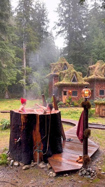 an outdoor hot tub in the middle of a wooded area with trees and grass huts