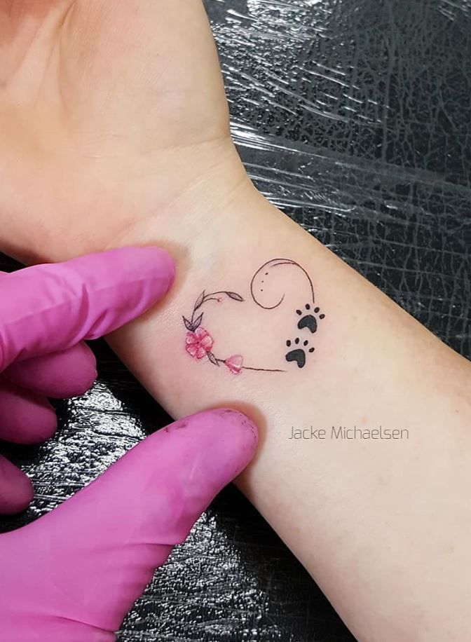 a person with a tattoo on their wrist holding onto another persons arm and the other hand has a dog's paw in it