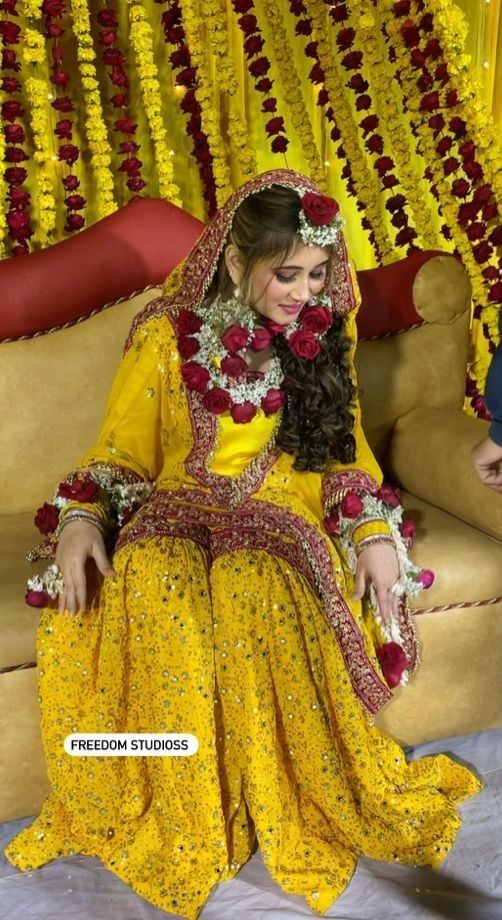 a woman sitting on top of a couch wearing a yellow dress and red flowers in her hair