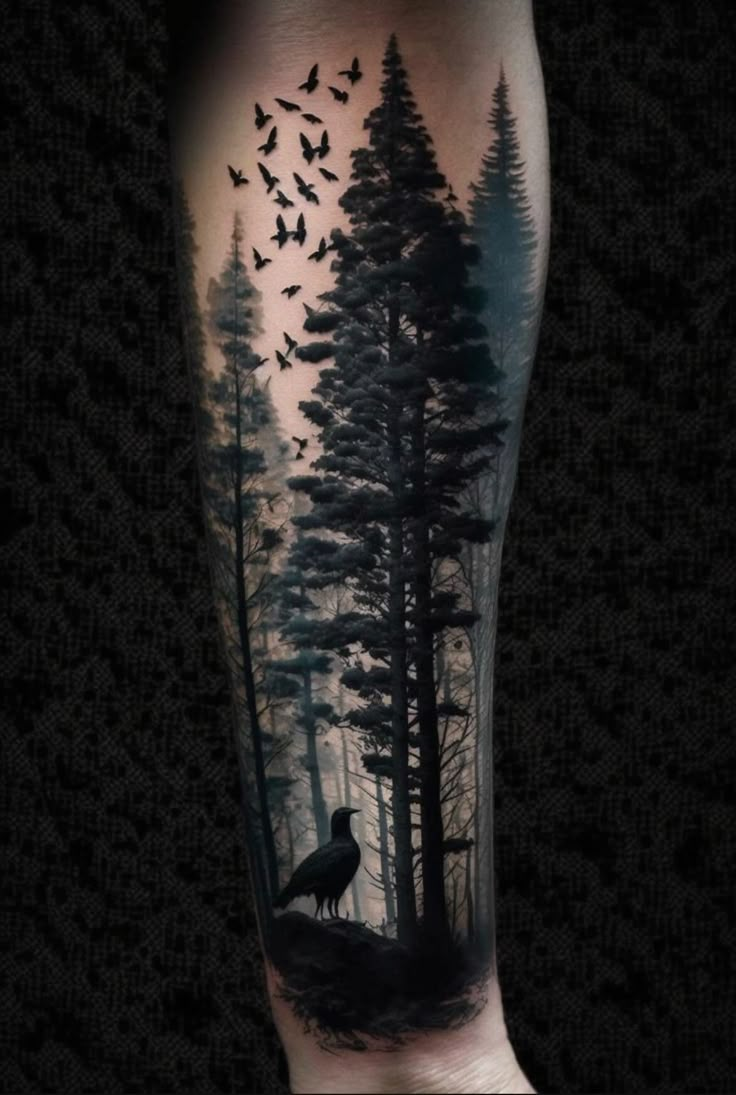 a man's arm with a black and grey tattoo on it that has birds flying over the trees