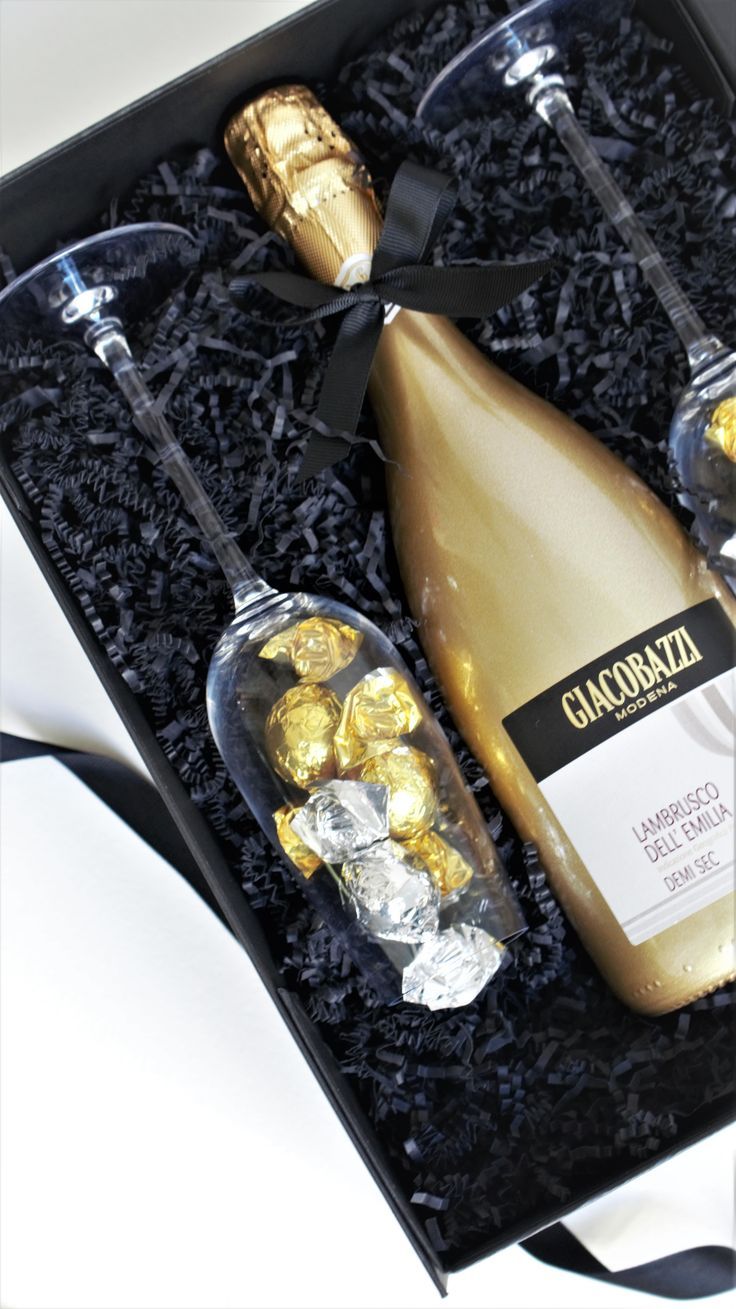 two champagne bottles and some chocolates in a black box with ribbon around the neck