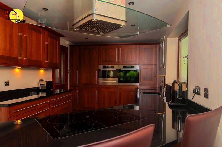 a modern kitchen with wooden cabinets and black counter tops, along with an oven hood over the stove