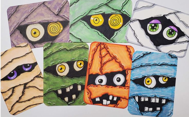 four coasters with different colored faces and eyes on them, all decorated to look like monsters