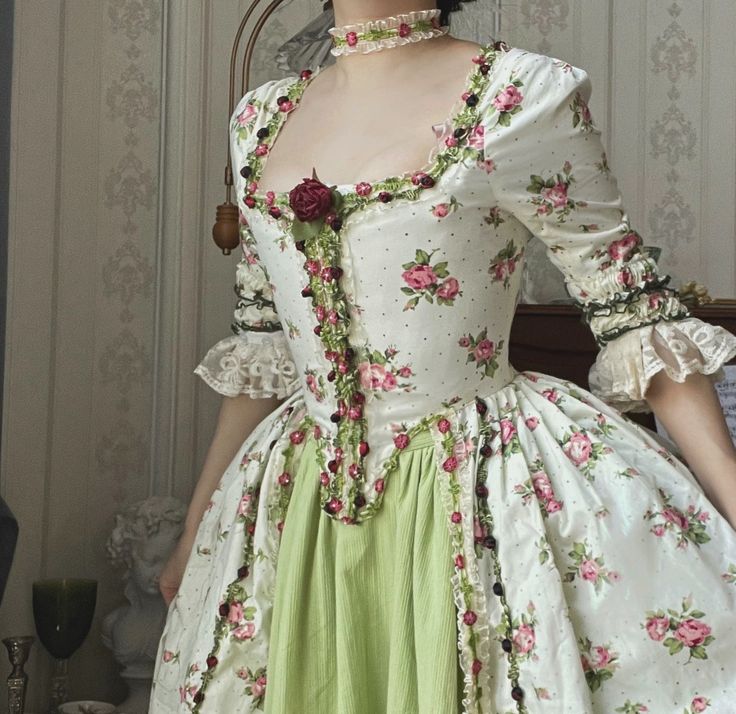 Immerse yourself in the opulent elegance of the Rococo era with our stunning Marie Antoinette-inspired ball gown. This exquisite dress, featuring a pastel green skirt and a pink floral bodice, seamlessly blends historical charm with modern sophistication, making it the perfect choice for a fairy-tale wedding. Rococo Style Elegance: This gown showcases the intricate detailing of Rococo fashion, with a structured bodice adorned with delicate lace and floral embroidery. Luxurious Craftsmanship: The dress is embellished with charming pink and green floral accents and intricate lace trim, creating a rich and opulent look that exudes timeless beauty. Corset Back Design: The elegant lace-up corset back not only adds to the historical allure but also ensures a perfect fit, enhancing your silhouett Rococo Style Fashion, French Rococo Fashion, Rococo Clothing, Rococo Inspired Fashion, Rococo Fashion 18th Century, Rococo Fashion Modern, Pastel Corset, Pink Green Outfit, Rococo Dresses