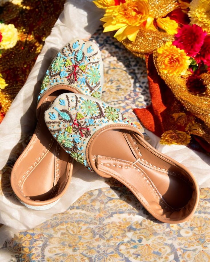 a pair of women's shoes sitting on top of a table next to flowers