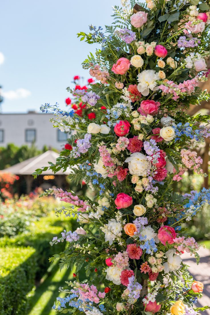 an arrangement of colorful flowers is growing on the side of a pole in a garden