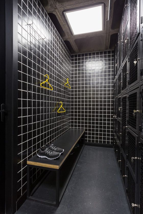 a room with black and white tiled walls and shelves filled with lockers that have yellow letters on them