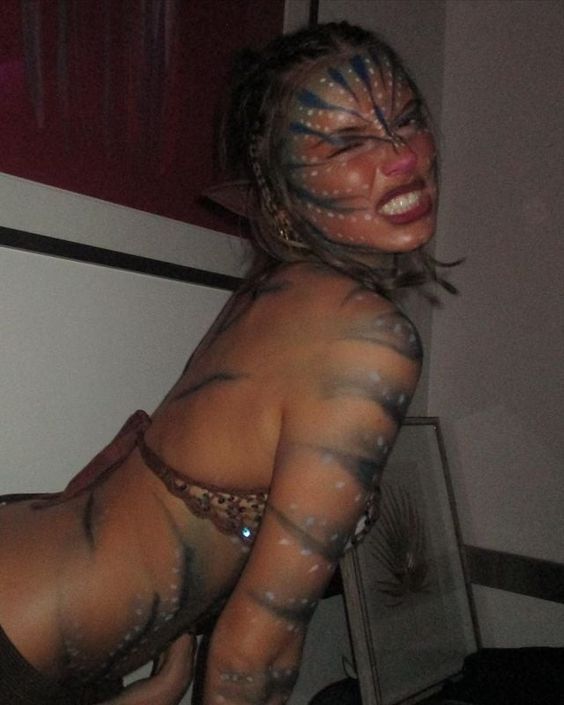 a woman with painted face and body poses for the camera