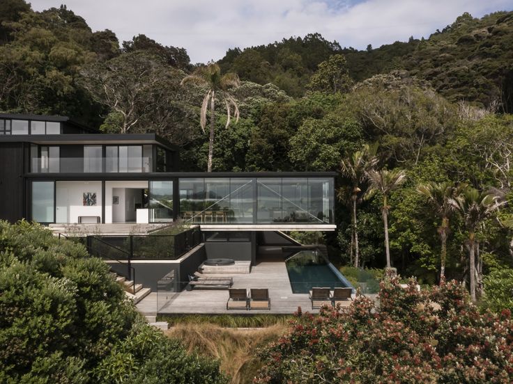 an aerial view of a modern house in the middle of some trees and bushes, surrounded by greenery