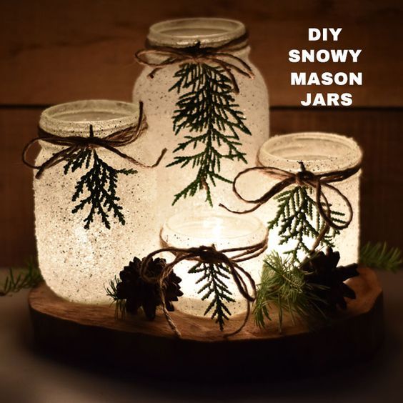 three mason jars with pine cones and evergreen branches in them