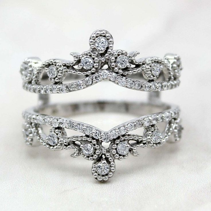 a white gold ring with diamonds in the middle and an intricate design on it's side