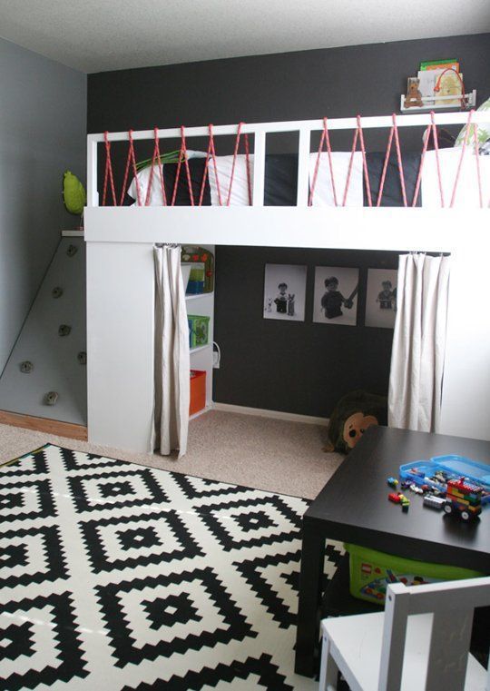 a bedroom with a loft bed and toy cars on the bottom bunk, in front of a black and white rug