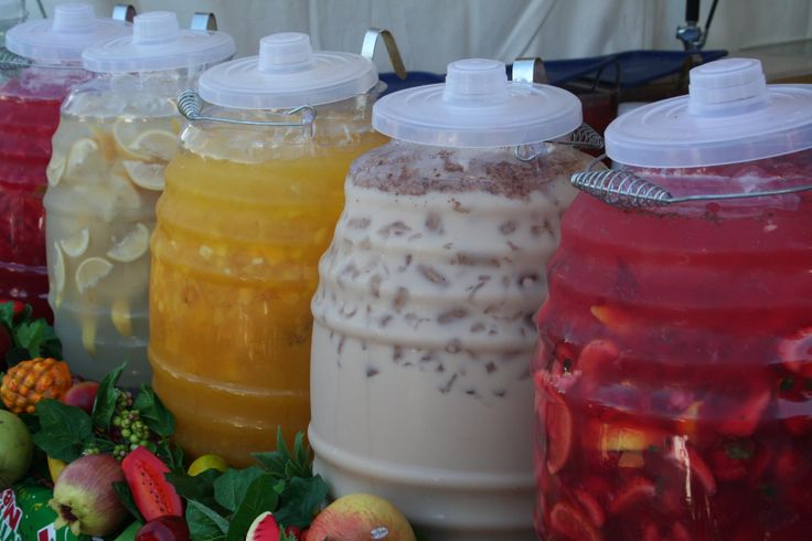 there are many different types of drinks in plastic containers on the table with strawberries