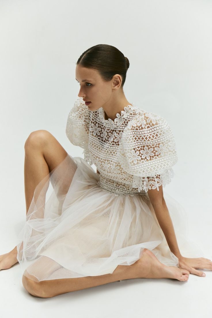 a woman is sitting on the floor wearing a white dress and high heeled shoes