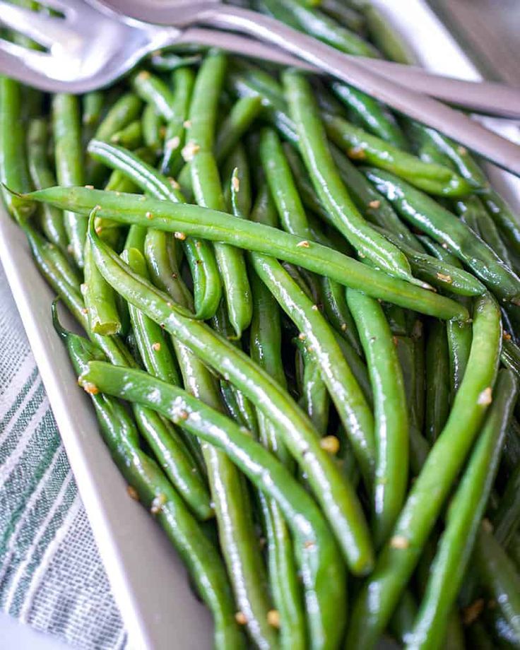 green beans are in a white dish with silverware