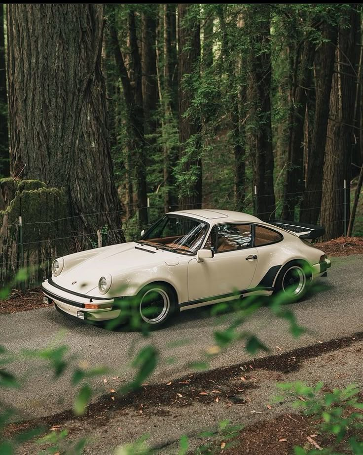 an old car is parked on the side of the road in front of some trees