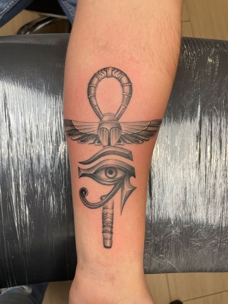 an egyptian tattoo with an eye and an all seeing symbol on the arm, in black ink