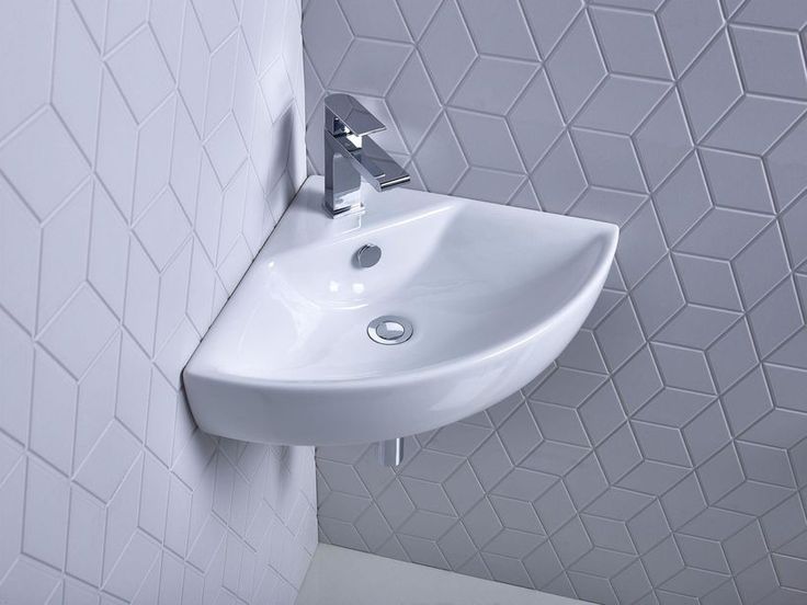 a white bathroom sink mounted to the side of a wall next to a tiled wall