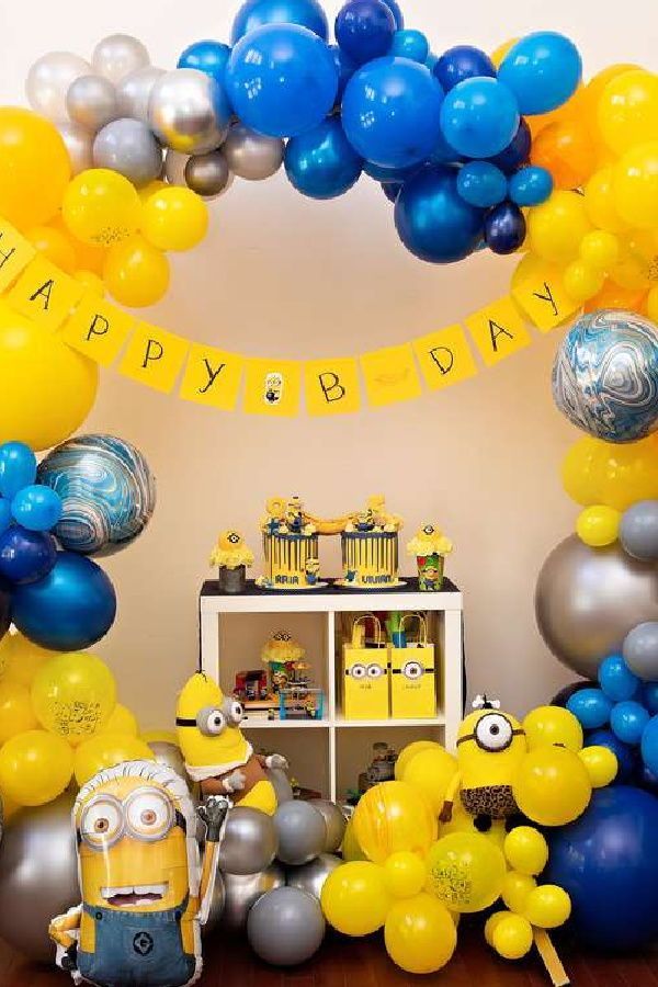 a birthday party with balloons and minion decorations on the floor, including an arch that says happy birthday