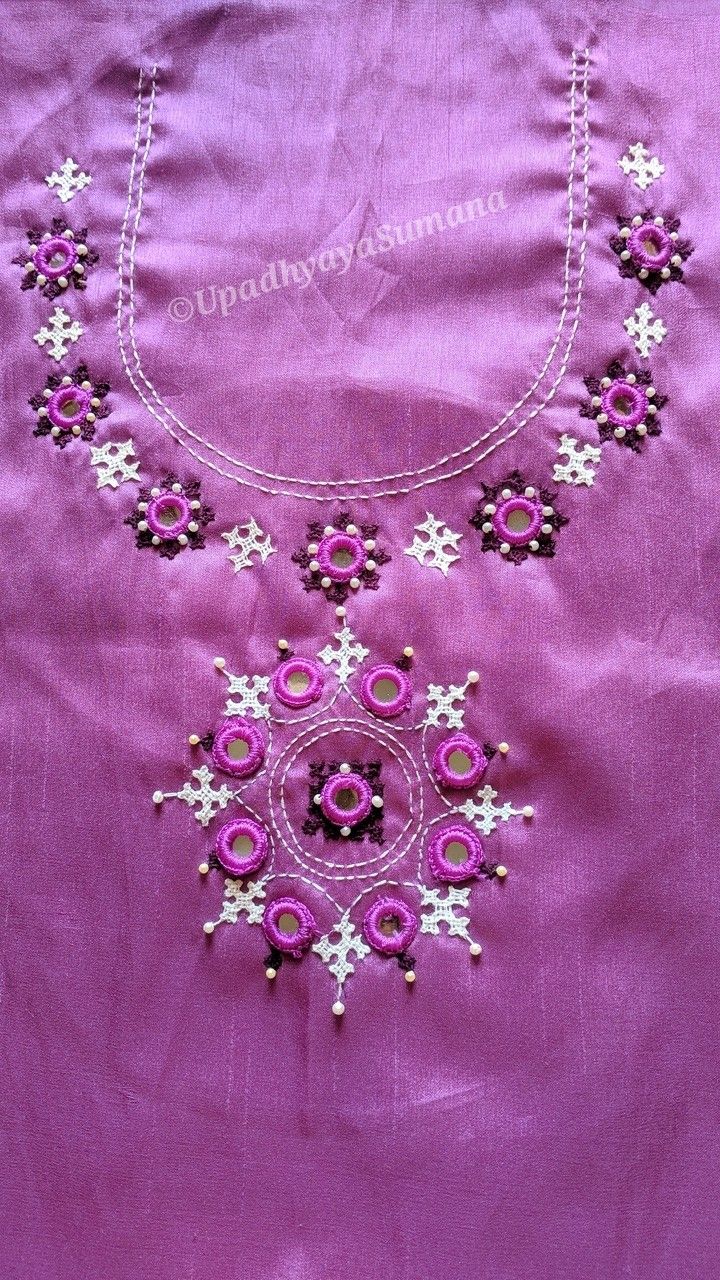 an embroidered necklace is displayed on a purple cloth