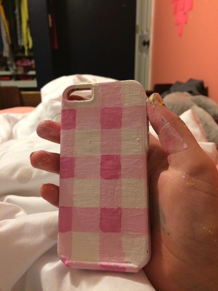 a hand holding a pink and white checkered phone case in it's palm