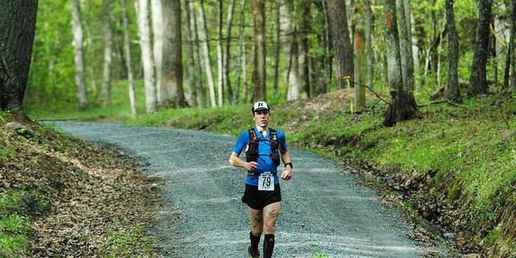 a man running down a dirt road in the woods