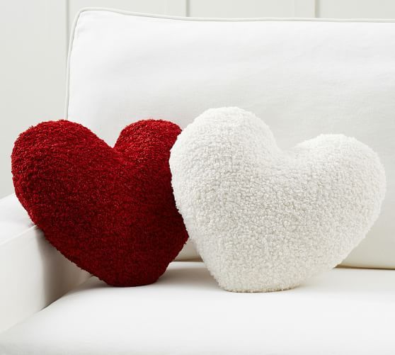 two red and white heart shaped pillows sitting on a white couch next to each other