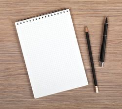 a notepad, pen and pencil sitting on top of a wooden table next to each other