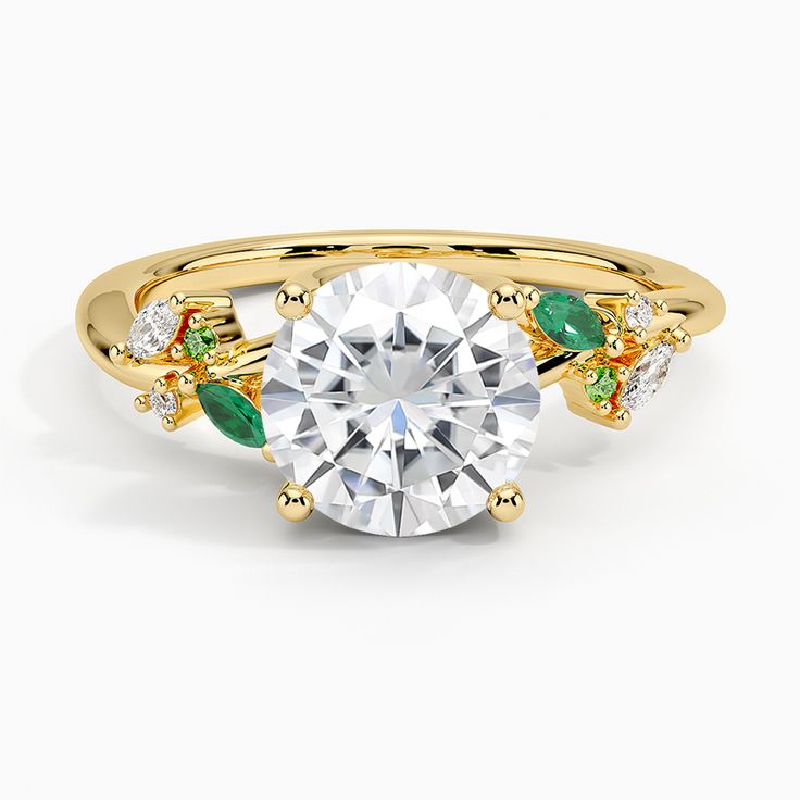 a yellow gold ring with green and white stones on the side, surrounded by leaves