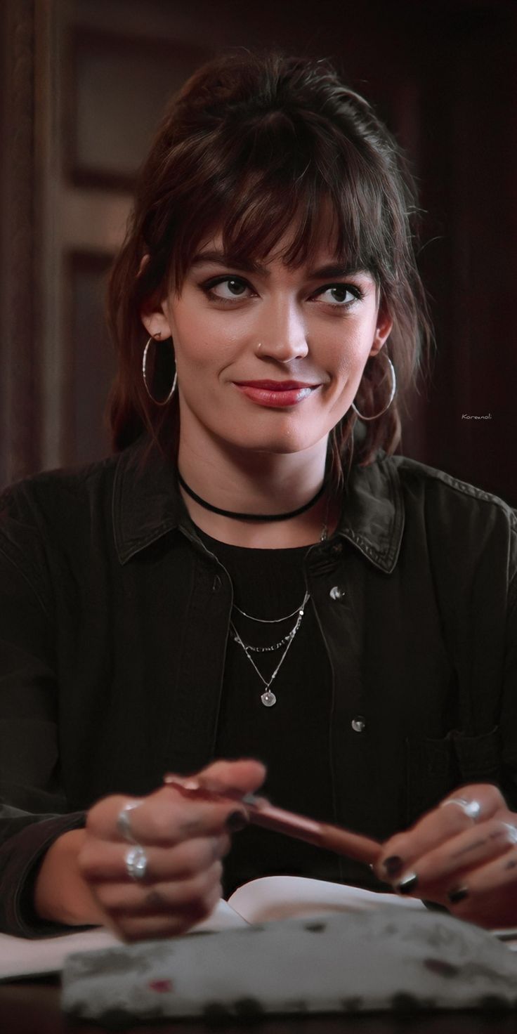 a woman sitting at a table with a pen in her hand