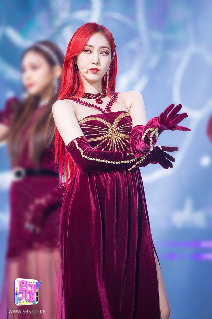 a woman with red hair wearing a long purple dress and holding her hands out to the side