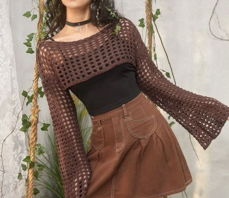 a woman is posing on a swing with her hands in her pockets and wearing a brown skirt