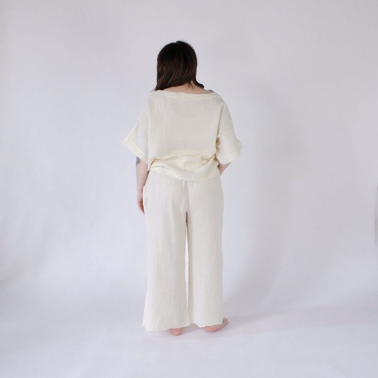 This is loungewear without limits. Comfortable and classy - this one-sized boat top is ideal for those looking to feel luxurious at home, on the town, with glam or on the go. Made with a luxe fabric composed of doubled Turkish muslin cotton. The crinkle muslin texture is incredibly soft on the skin, and feels lightweight, yet substantial when worn. Designed in an oversized style, the Crinkle Crop Top has half sleeves, with a cropped cut at the waist, and a boat neckline. Available in two color s Cream Linen Tops For Loungewear, Cream Linen Loungewear Tops, Cream Tops For Spring Lounging, Cream Tops For Lounging In Spring, Beige Cotton Top For Lounging, Beige Cotton Blouse For Loungewear, Beige Cotton Lounging Top, White Linen Tops For Loungewear, White Linen Top For Loungewear