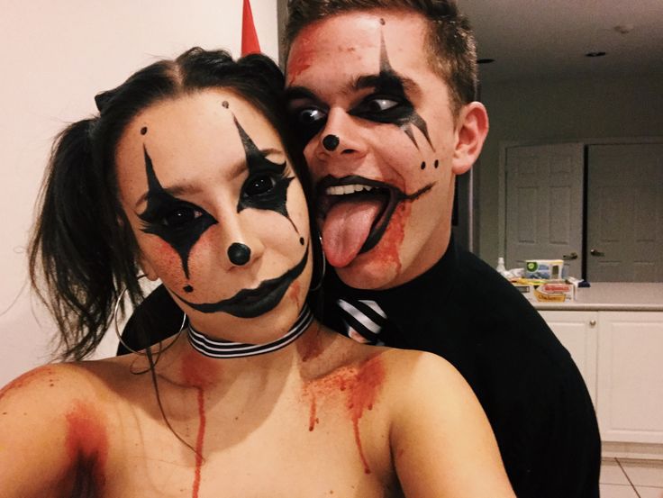 a man and woman with painted faces posing for a photo in front of a mirror