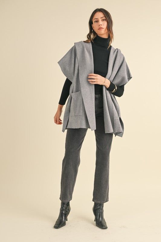 The Grey Open Hoodie Cardigan is the perfect addition to any wardrobe. Made from a cozy sweater knit, it features a stylish open front design with front pockets and a hoodie for added warmth. This versatile cardigan is perfect for layering all year long and can be paired with our basic long sleeve tops and wide leg cotton pants for a relaxed, yet elevated look. Trendy Sweater Coat With Pockets For Cold Weather, Trendy Knit Outerwear With Pockets, Knit Sweater Coat With Pockets For Cold Weather, Solid Knit Outerwear For Loungewear, Knit Outerwear With Pockets For Cold Weather, Knit Outerwear For Loungewear In Solid Color, Cozy Gray Sweater With Pockets, Gray Sweater With Pockets For Layering, Gray Layering Sweater With Pockets