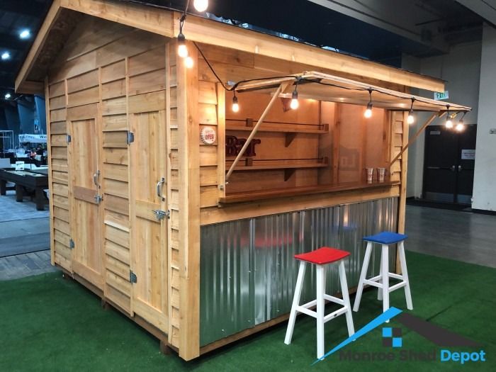 an outdoor bar with two stools in front of it and lights hanging from the ceiling