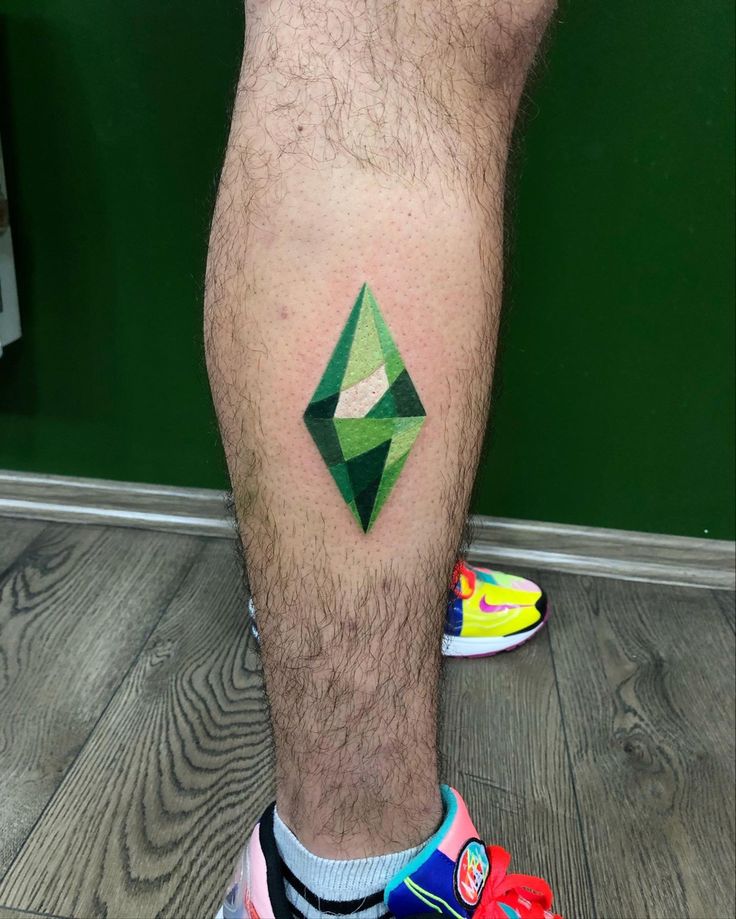 a man's leg with a green diamond tattoo on his left calf and colorful sneakers